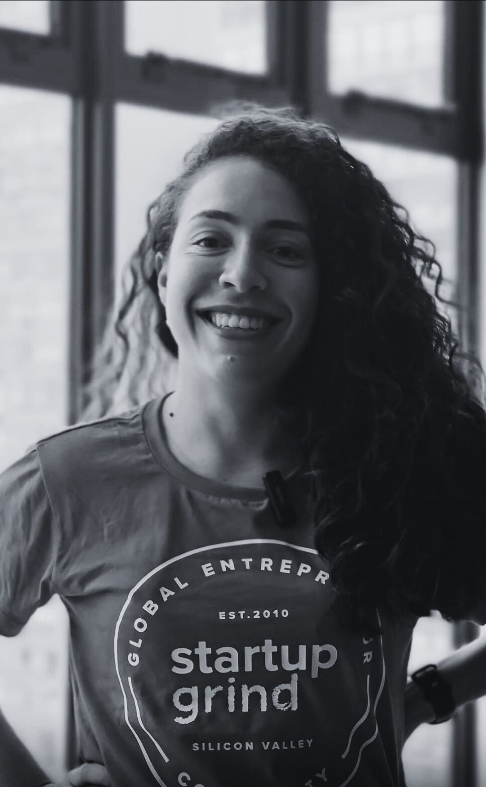 Karina Romano com a camiseta do Startup Grind, olhando para a janela