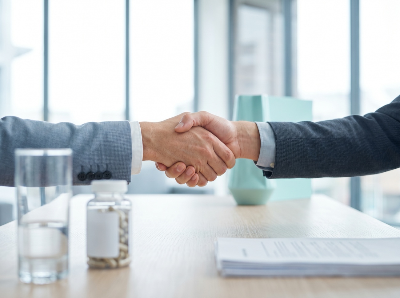 A handshake between two business partners over a desk